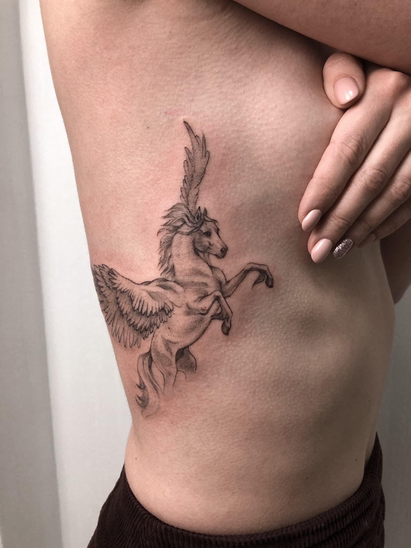 Fine-Line-Pegasus-Tattoo an den Rippen