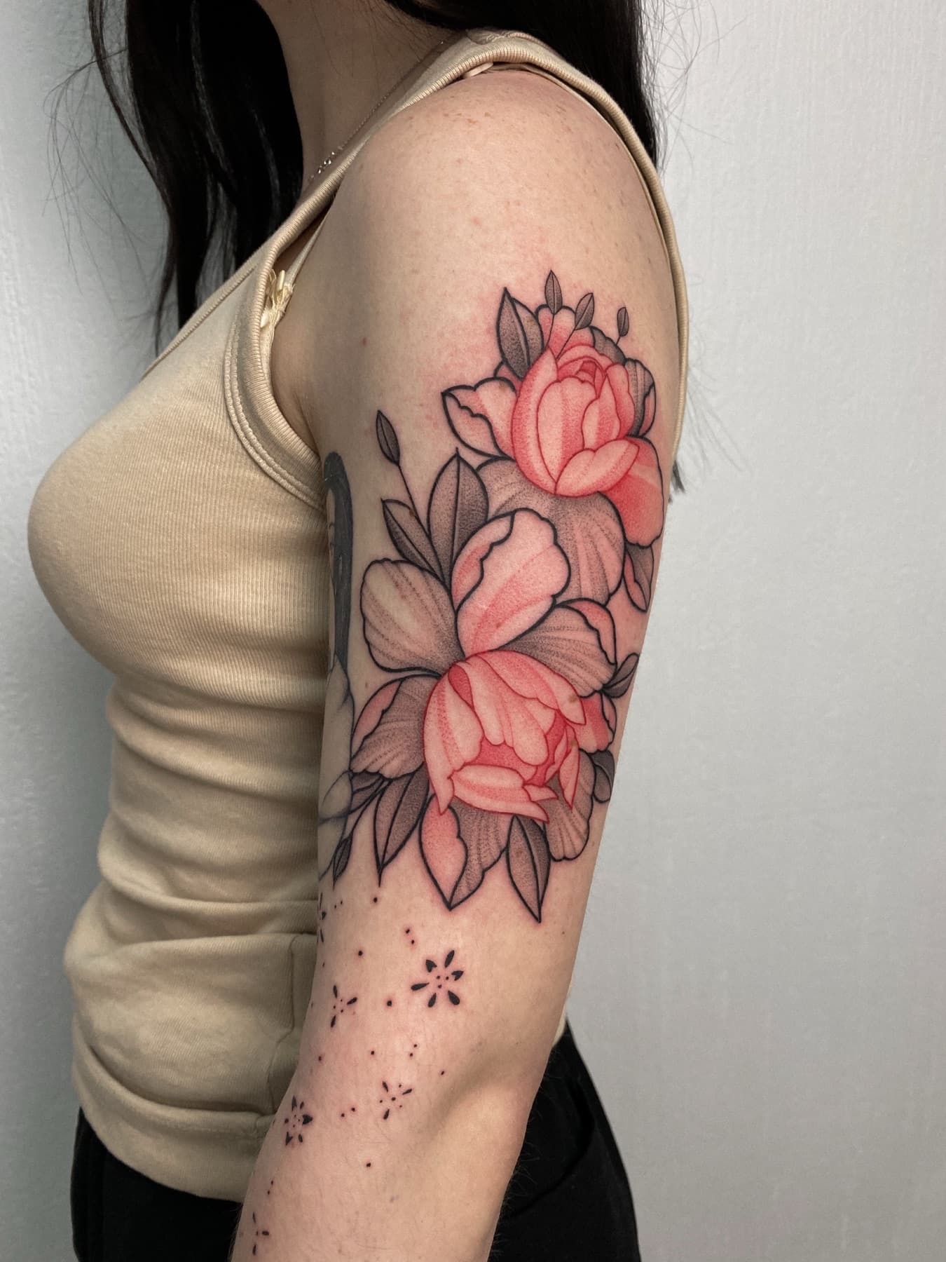 Farbiges Fine-Line-Pfingstrosen-Tattoo mit Sternen am Oberarm