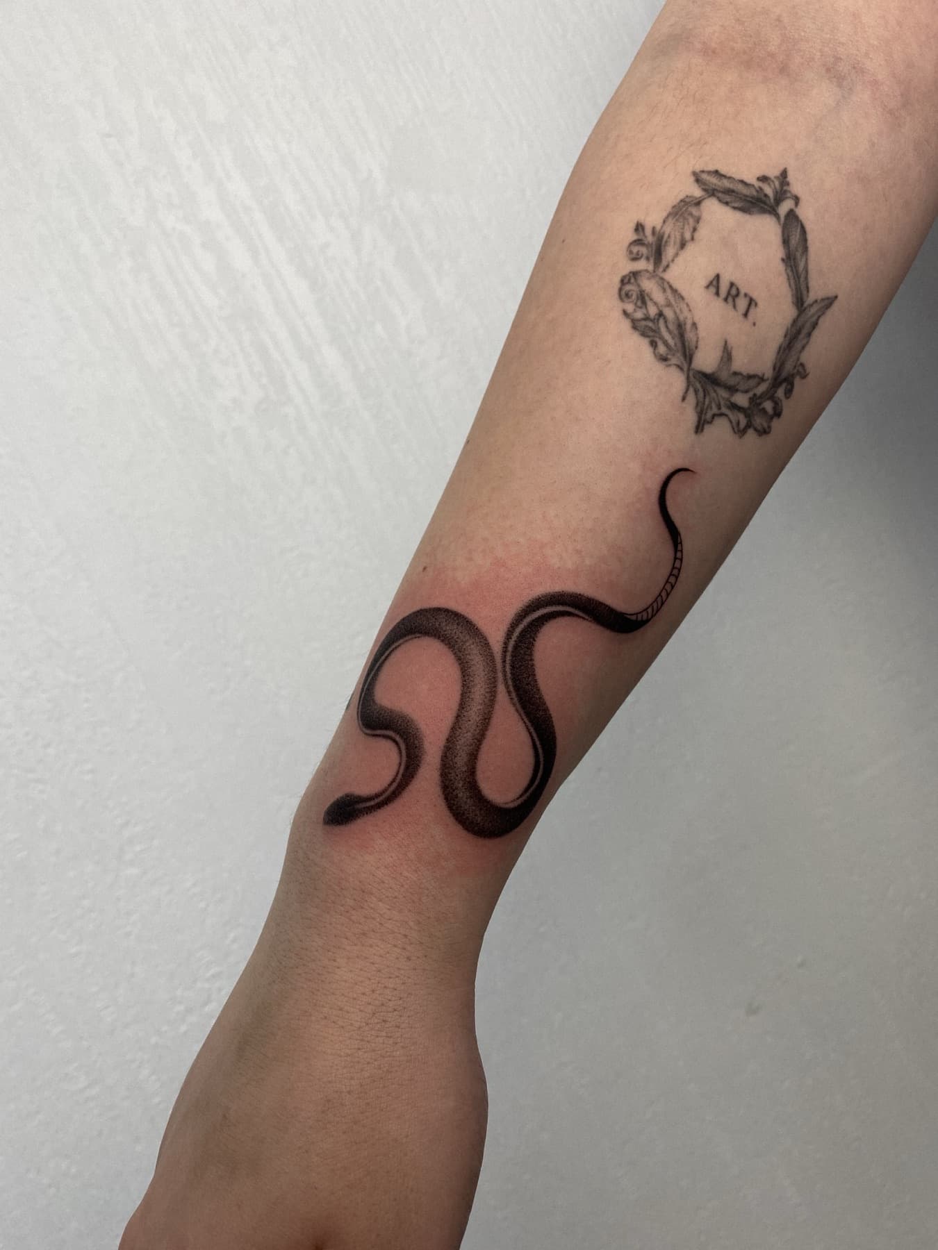 Fine-Line-Schlangen-Tattoo am Unterarm