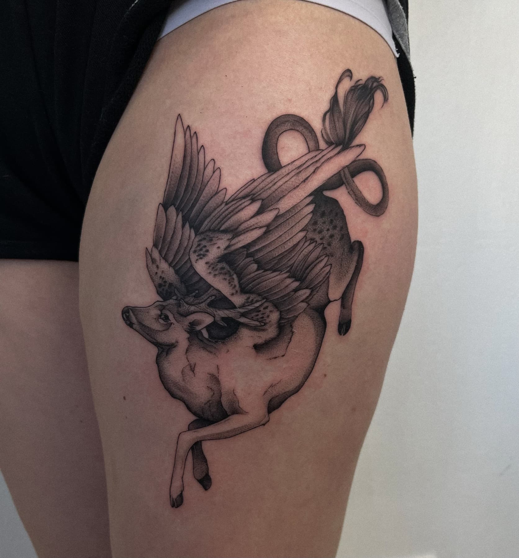 Illustratives Tattoo eines geflügelten Rehs am Oberschenkel