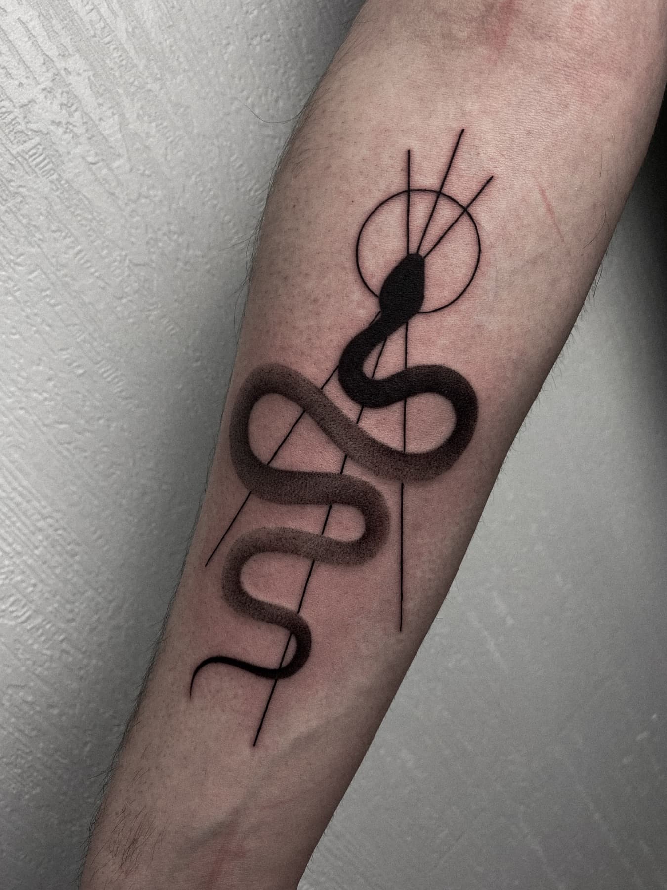 Fine-Line-Schlangen-Tattoo mit geometrischer Sonne