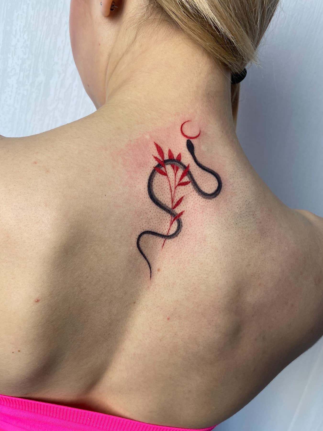 Fine-Line-Schlangen-Tattoo mit Zweig im Nacken