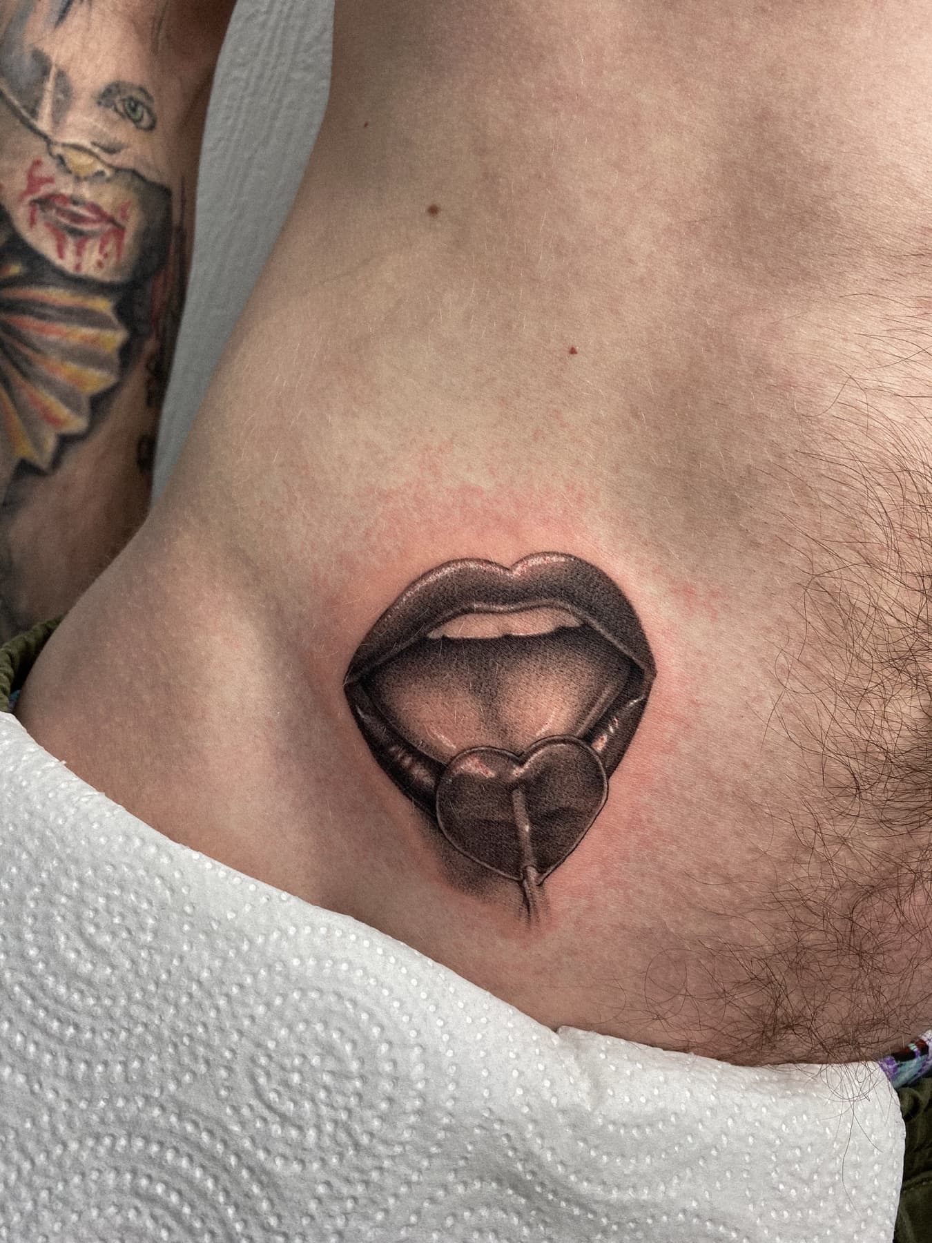 Illustratives Tattoo von Lippen mit Lolli an den Rippen
