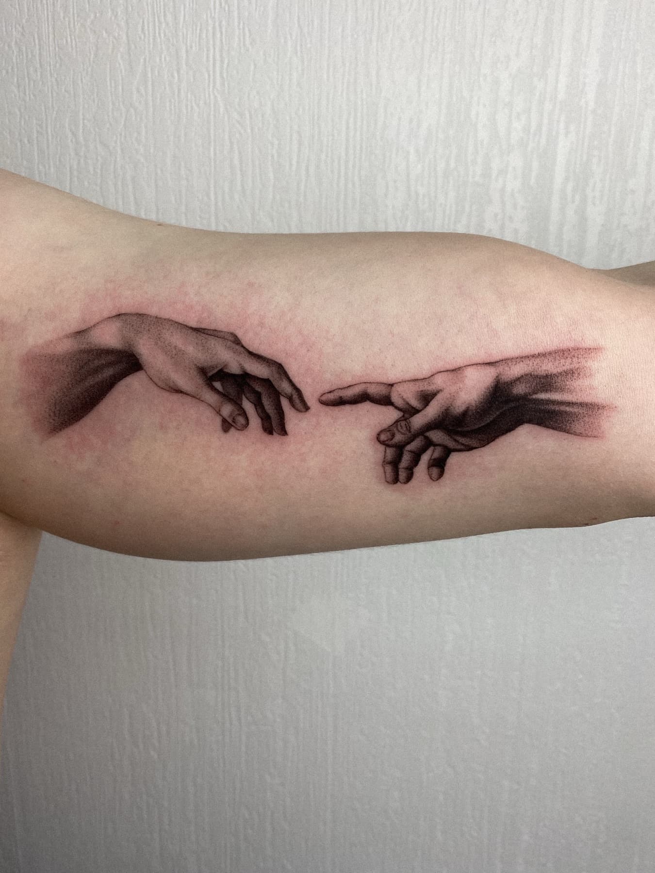 Illustratives Tattoo sich berührender Hände, angelehnt an Michelangelo