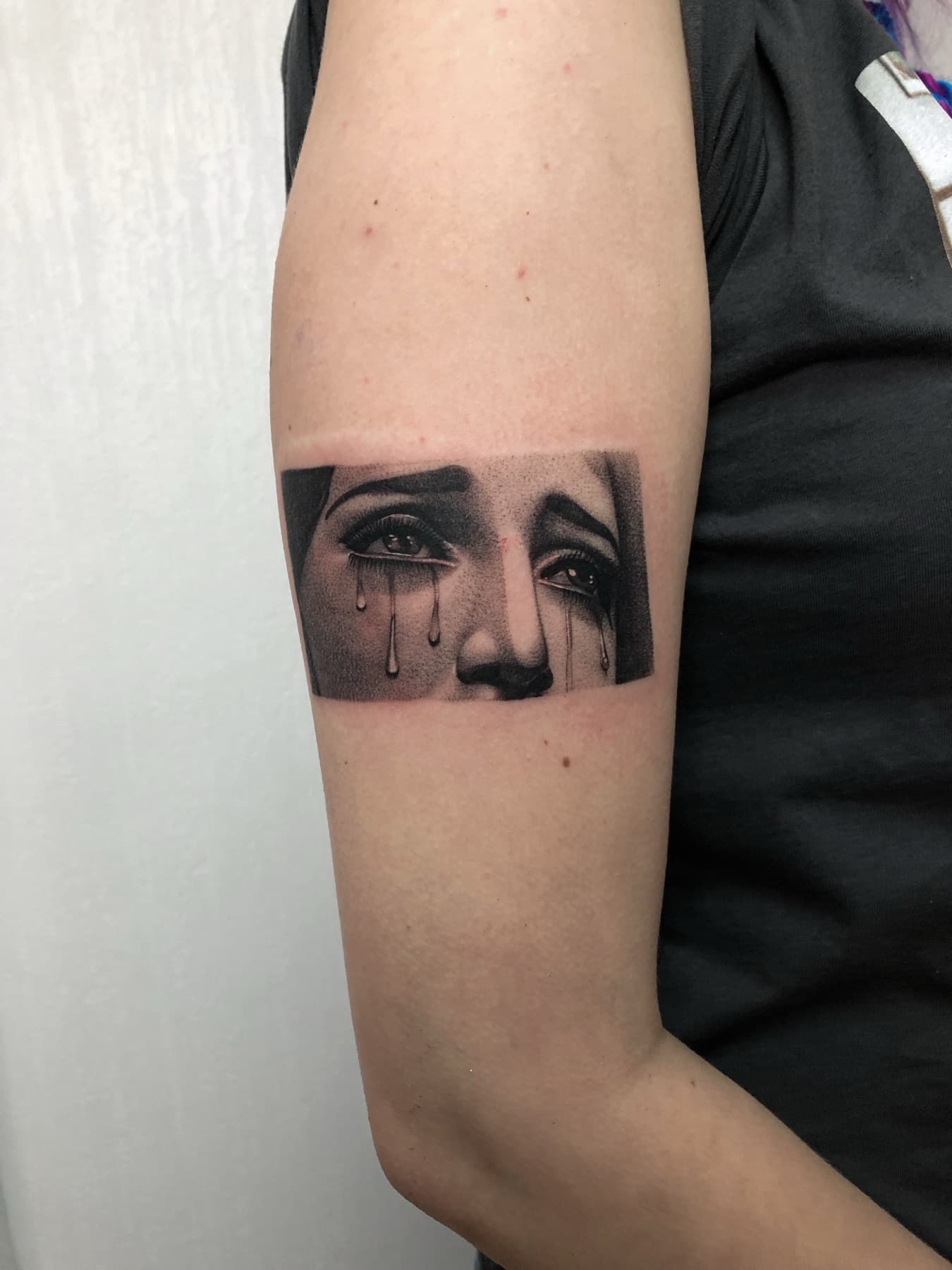 Micro-Realism-Tattoo weinender Augen am Oberarm