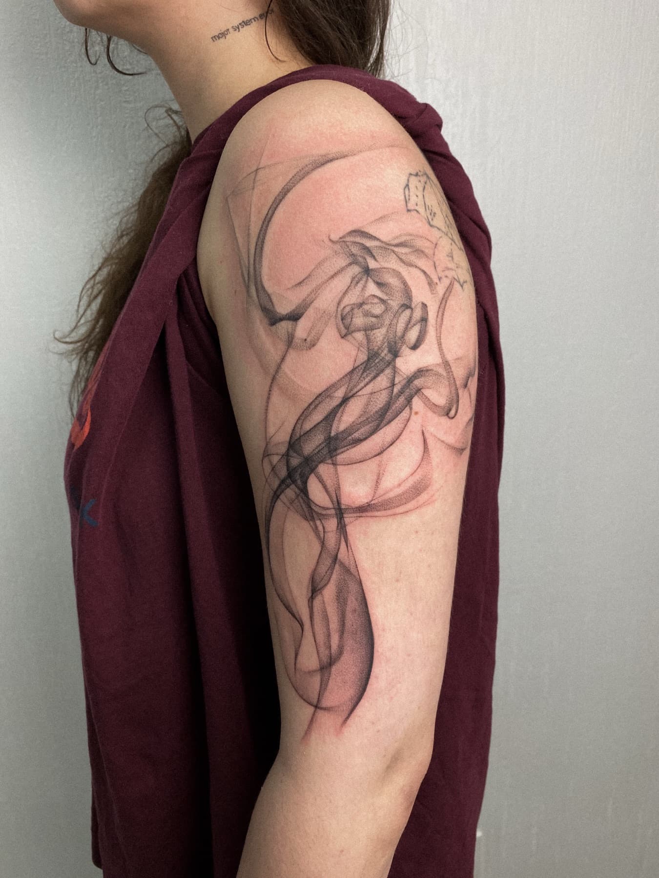 Abstraktes Fine-Line-Tattoo an der Schulter