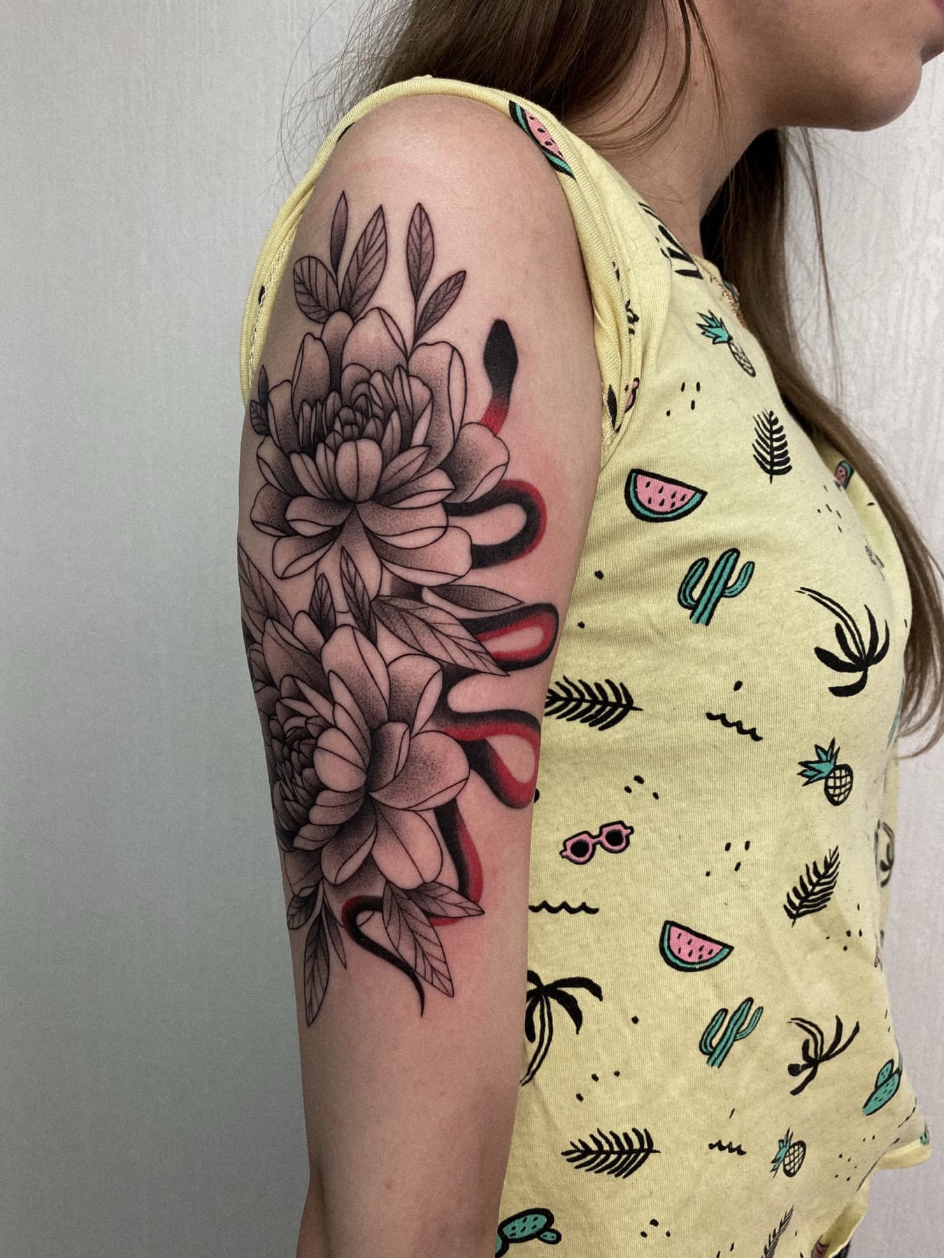 Fine-Line-Pfingstrosen-Tattoo mit roter Schlange am Oberarm