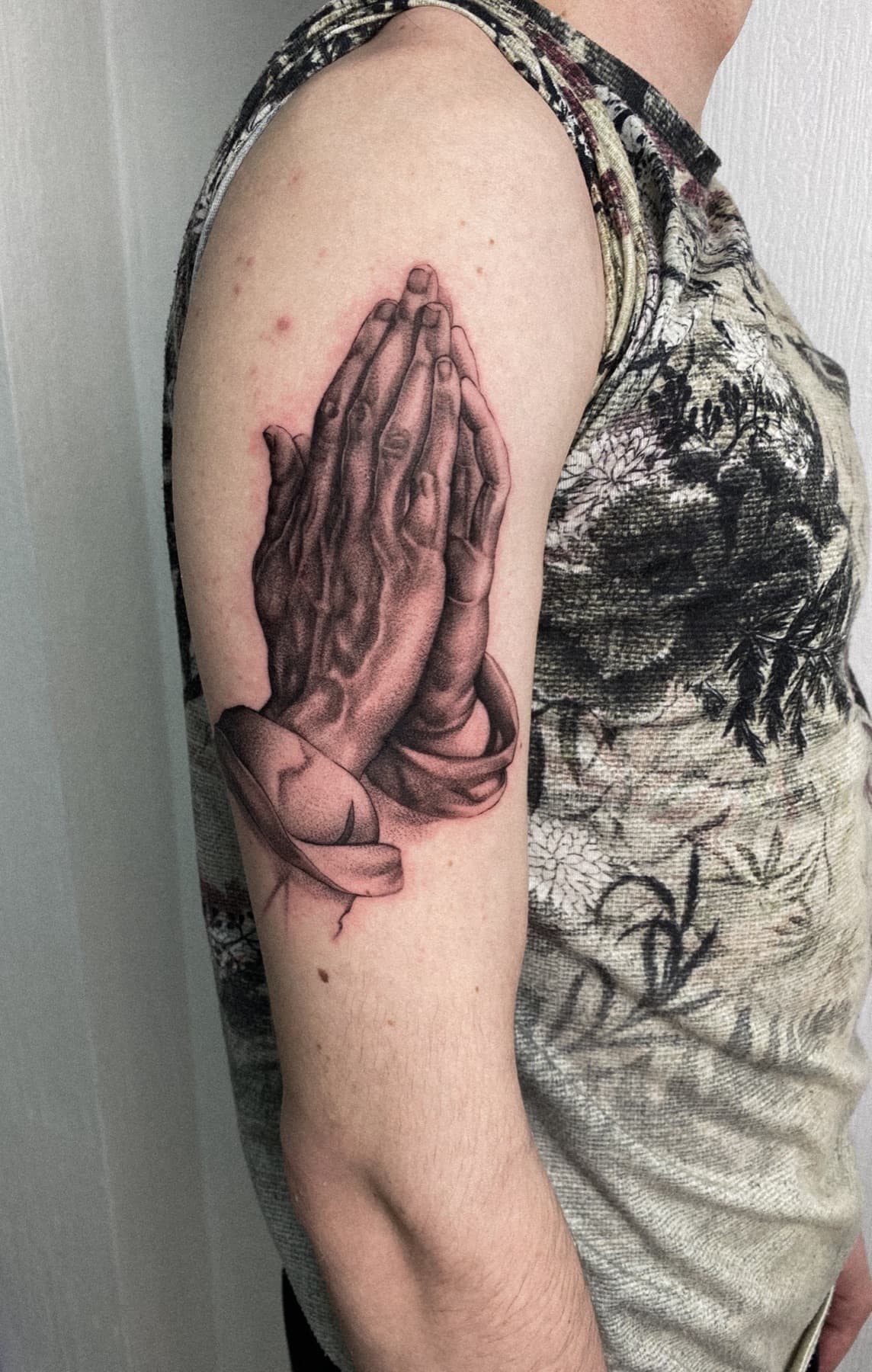 Micro-Realism-Tattoo betender Hände am Oberarm