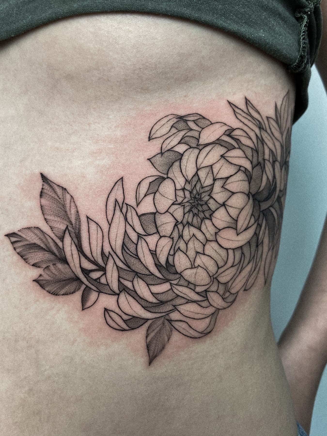 Fine-Line-Chrysantheme-Tattoo an den Rippen