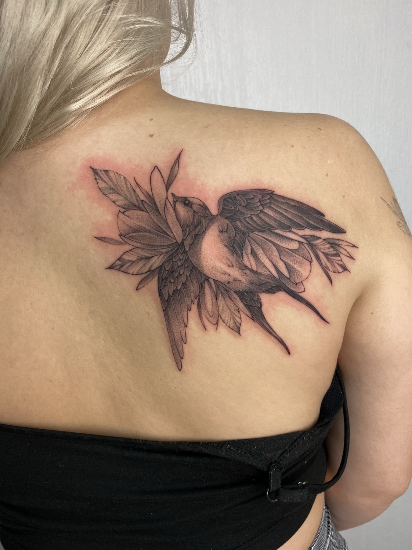 Fine-Line-Vogel-Tattoo mit Blättern am Schulterblatt